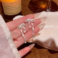 Close-up of silver bow earrings with a clear teardrop cubic zirconia pendant detail - A1913 Silver