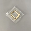 Transparent PVC zip bag containing large square golden metal earrings on grey background - Slider Bag 8*8cm