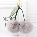 Detailed view of gray faux fur cherry keychain with green leather leaves and gold hardware - Light Gray