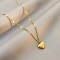 Minimalist gold heart necklace with love engraving on soft beige fabric background - Heart Necklace / Gold