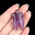 Pendentif dent en agate violette tenu à la main avec bélière métallique pour collier - Améthyste
