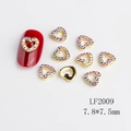 Golden hollow heart nail charms with AB rhinestones and red manicure display - LF2009 Gold Aurora Rhinestone Hollow Heart