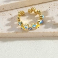 Vista macro de anillo dorado con ojos de la suerte sobre fondo de piedra natural - Ojos Múltiples Esmalte Amarillo