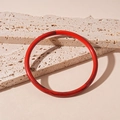 Gros plan d'un bracelet en acrylique rouge avec texture marbrée sur fond de pierre beige - Bracelet-Rouge