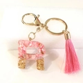 Macro shot of letter R resin keychain with pink shells, gold glitter and tassel - Letter R