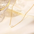 Dettaglio del ciondolo con perla bianca su catena dorata posata su un tessuto di seta - Oro (N377)