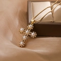Collana a croce placcata oro con perle e zirconi su sfondo in seta morbida - Oro