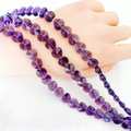 Dark purple faceted heart-shaped crystal glass beads for jewelry making on model hand - Violet
