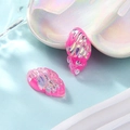 Macro-opname van twee roze hars schelphangers met iriserende glitters op een bordje - Rozerood