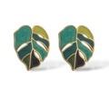 Golden monstera leaf stud earrings with green enamel and heart charm in a flat lay view - Green Monstera Leaf Style