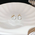 Detalle de pendientes de gota de plata con piedras de ojo de gato en plato de cerámica - Pendientes de aro con gota de agua de piedra de ojo de gato plateada