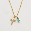 Macro shot of gold cross necklace with clear zircons and blue rectangular gemstone pendant - December / Deep Blue