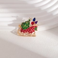 Détail d'une broche traîneau de Noël dorée festive avec cadeaux colorés en émail - Traîneau de Noël