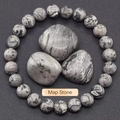 Macro shot of natural grey map stone beaded bracelet and polished raw stones with labels - Map Stone