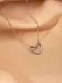 Vue macro d'un pendentif coeur argenté sur une chaîne serpent sur du tissu en soie - Cœur Argenté