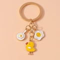Niedlicher Schlüsselanhänger mit Spiegelei, Küken und Pfanne an goldenem Ring auf Beige - Ei und Huhn