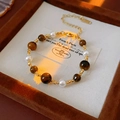 Detailed close-up of tiger eye beads and pearls on a gold-plated beaded bracelet - Golden Coffee