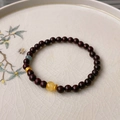 Detail of sandalwood bead bracelet with amber and turquoise charms on a vintage porcelain plate - Sandalwood Blue Crystal Amber Bracelet