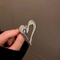 Dettaglio di una spilla a forma di cuore in metallo argento dal design minimalista e lineare - Argento