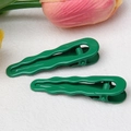 Close-up of green wavy water drop hair clips on soft fabric with tulip decor - Christmas Green