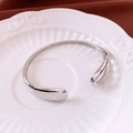 Macro detail of silver hollow cuff bracelet resting on white decorative ceramic plate - Silver Electroplated / Silver