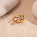 Detail of gold open ring with marquise-cut zircon set against beige stone and plaster - Gold Rhombus Double Layer
