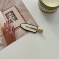 Detail van de minimalistische zwart-witte haarclip op een vintage kunstboek achtergrond - Wit