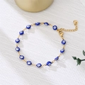 Close-up of blue enamel evil eye charm bracelet with golden chain and lobster clasp - Blue Eyes Gold