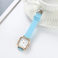 Dettaglio della piccola cassa quadrata dorata e del cinturino in pelle azzurro chiaro - Celeste