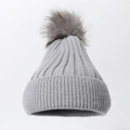 Close-up of grey knit beanie with large faux fur pom-pom and vertical ribbed texture - Gray