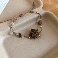 Close-up of star-shaped tiger eye stone and crystal beads on woven cord bracelet - Tiger Eye Star Pendant / Brown