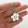 Detailed close-up of a silver flower pendant necklace with an engraved hollow smiley face - Flower Steel