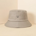 Close-up of khaki cotton bucket hat with a minimalist black embroidered smiley face detail - One Size / Khaki