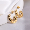 Close-up of golden U-shaped earrings with star pattern engraving on white silk - Gold Oval Star