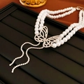 Macro shot of double-layer faux pearl necklace with diamond butterfly tassel pendant - Butterfly Pearl Tassel Style / Silver