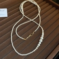Détail d'un collier de perles blanches avec fermoir doré sur un coffret en velours brun - Or-Blanc