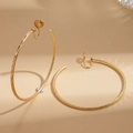 Detail eines mattierten 18k vergoldeten Clip-Ohrrings auf warmem beigefarbenem Hintergrund - Clip-on (18K Echt Vergoldet) / Gold
