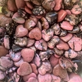 Macro shot of bulk heart-shaped pink rose quartz stones with natural black veining - Rhodonite with Wood Grain