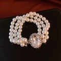Détail d'un bracelet de perles à trois rangs avec un grand strass ovale sur cuir noir - Bracelet Décoratif en Perles à Trois Rangs avec Strass Ovale