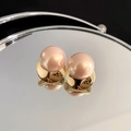 Vue macro de la boucle d'oreille perle rose avec base dorée sur une surface miroir - Style Rond Doré (25#)