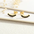 Macro shot of 18K gold plated studs with curved black zircon stones on white floral background - Black Arc Rows Zirconia (ER1197-J)