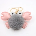 Detail of cute crab keychain with grey fluffy fur ball and pink leather claws and legs - Gray