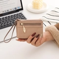 Close-up of a nude lychee grain leather wallet with a leaf-shaped zipper and wrist strap - Apricot