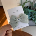 Close-up of a green fabric bow hair clip with a vintage-style decorative button - Avocado Green Bowknot Duckbill Clip