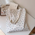 Close-up of white floral cotton tote bag featuring red berry patterns and woven label - White Base With Blue Leaves And Red Fruit