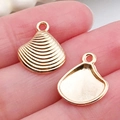 Golden seashell alloy charms for DIY bracelets necklaces shown in two pieces on fingertip - Shell Pendant 15x13mm