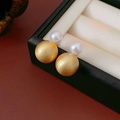 Makroaufnahme von gebürsteter Goldkugel und weißem Perlenohrring auf weißem Kissen - Gebürsteter Runder Perlen-Doppelperlen-Stil / Gold