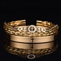Detail of two gold stainless steel bracelets with cross charms and engraved prayer - Gold Set C