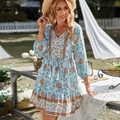 Abito boho azzurro con scollo a V, motivi floreali e nappe in un ambiente da giardino - S / Blu