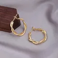 Elegant gold twisted hoop earrings with a spiral texture design on grey silk - Double Strand Twist / E-032---Gold